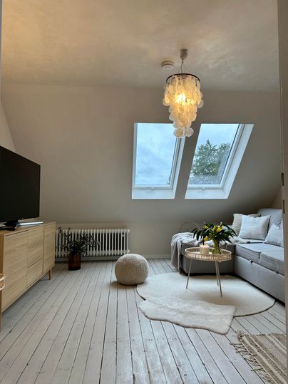 Een gezellige woonkamer met een heldere bank en grote dakramen. De ruimte is modern ingericht en zorgt voor een uitnodigende sfeer.