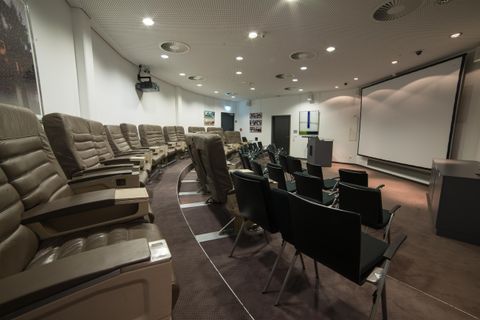 Ein moderner Besprechungsraum mit bequemen Sesseln und einem großen Bildschirm. Der Raum ist gut beleuchtet und hat eine elegante Atmosphäre.