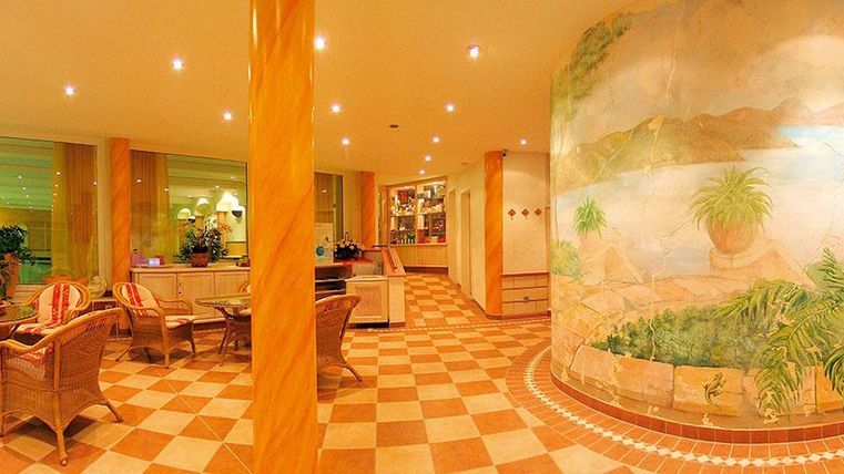 Ein einladender Innenbereich mit gemütlichen Sitzgelegenheiten und einer großen Wandmalerei. Die Beleuchtung ist warm und schafft eine entspannte Atmosphäre.