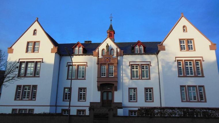 A historical building with a white facade and red accents. The sky is clear and blue.