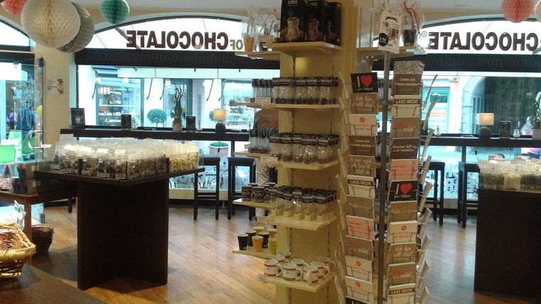 Ein elegantes Schokoladengeschäft mit einem offenen Raum. Regale sind mit verschiedenen Schokoladenprodukten und Dekorationen gefüllt.