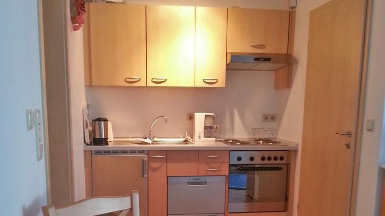 A modern kitchen with light wooden cabinets and stainless steel appliances. The room is well-lit and looks inviting.