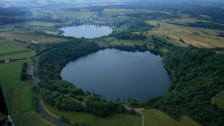 Een indrukwekkende luchtfoto van twee meren, omringd door weelderig groen en zachte heuvels. Het ontspannen landschap geeft een gevoel van rust en natuurverbondenheid.