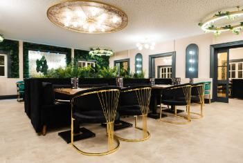 Ein eleganter Restaurantbereich mit stilvollen schwarzen Stühlen und goldenen Akzenten. Die grüne Dekoration und die indirekte Beleuchtung schaffen eine gemütliche Atmosphäre.