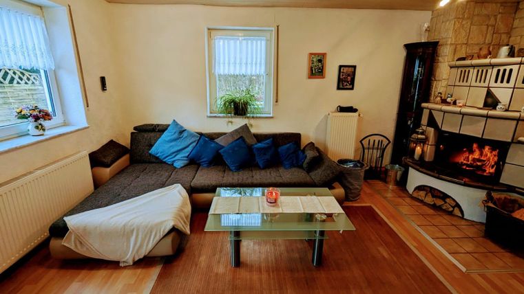 A cozy living room with a large sofa, colorful cushions, and a modern table. The fireplace creates a warm atmosphere.