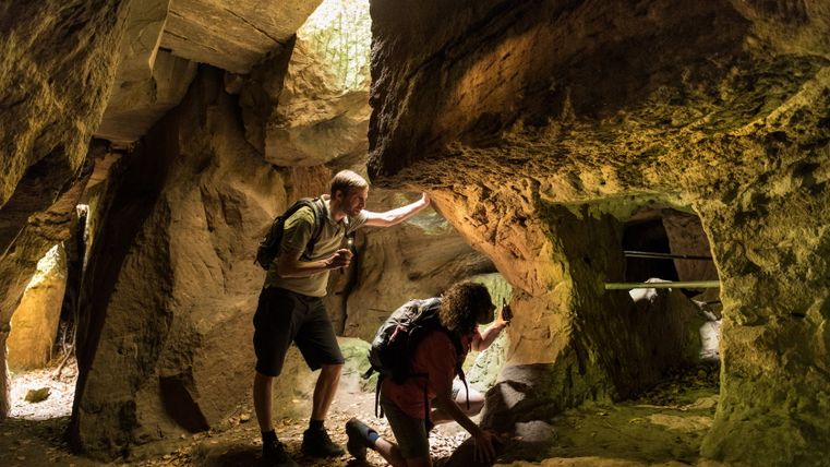 Two people explore an old mine with flashlights.