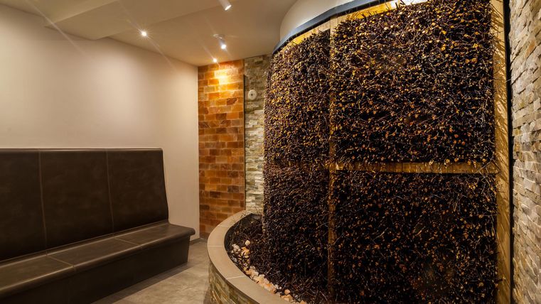 Ein moderner Raum mit einer Wand aus Naturmaterialien und einem gemütlichen Sitzbereich. Die sanfte Beleuchtung schafft eine entspannende Atmosphäre.