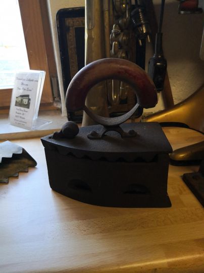 Ein antikanischer Holzgriff-Eisen auf einem Tisch. Der Eisen hat eine klassische Form und wirkt nostalgisch.