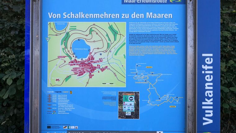 Ein Informationsschild über die Maare in der Vulkaneifel. Es zeigt eine Karte und beschreibt die Umgebung und Wanderwege.