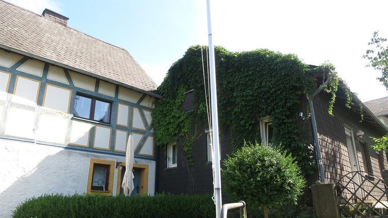 Een charmant gebouw in een traditionele vakwerkstijl met groene klimop. De tuin is verzorgd en biedt een uitnodigende sfeer.