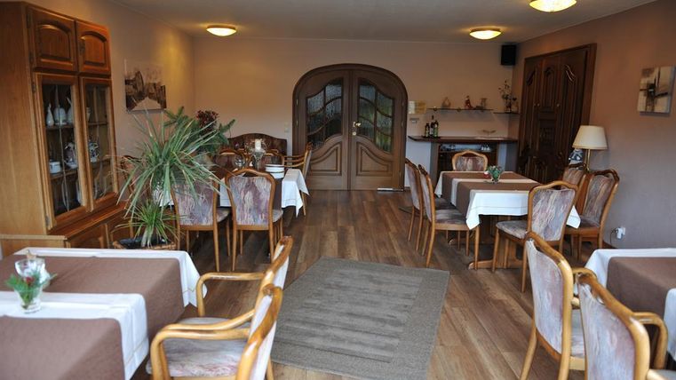 A cozy restaurant with wooden furniture and bright tables. The atmosphere is welcoming and friendly.