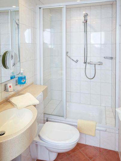 Een moderne badkamer met douche en wastafel. Schone tegels en lichte kleuren creëren een uitnodigende sfeer.