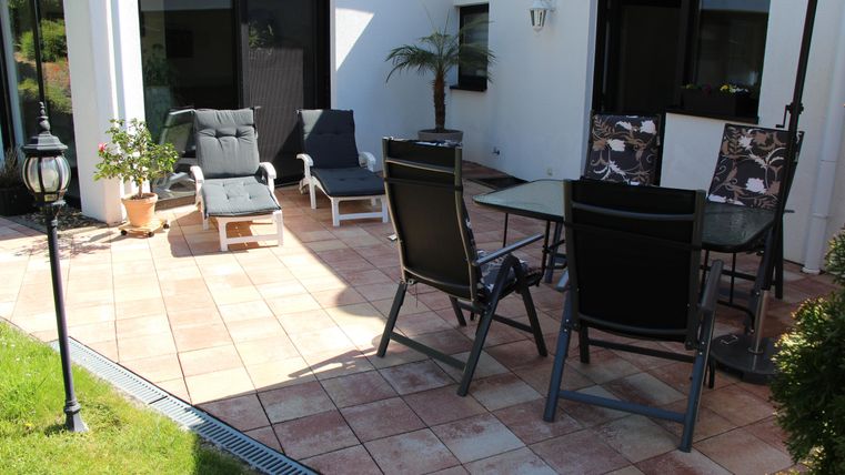 A cozy patio with modern garden furniture and a beautiful plant. The area is well-lit and perfect for relaxing outdoors.
