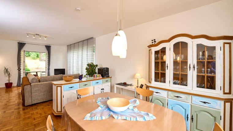 Ein gemütlicher Wohnbereich mit einem Ess Tisch und einer geschmackvoll eingerichteten Anrichte. Viel Licht fällt durch die Fenster und schafft eine einladende Atmosphäre.