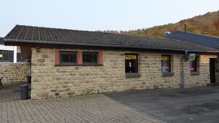 Ein kleines Steinhaus mit einem dunklen Dach. Es steht in einer ruhigen Umgebung, umgeben von Natur.