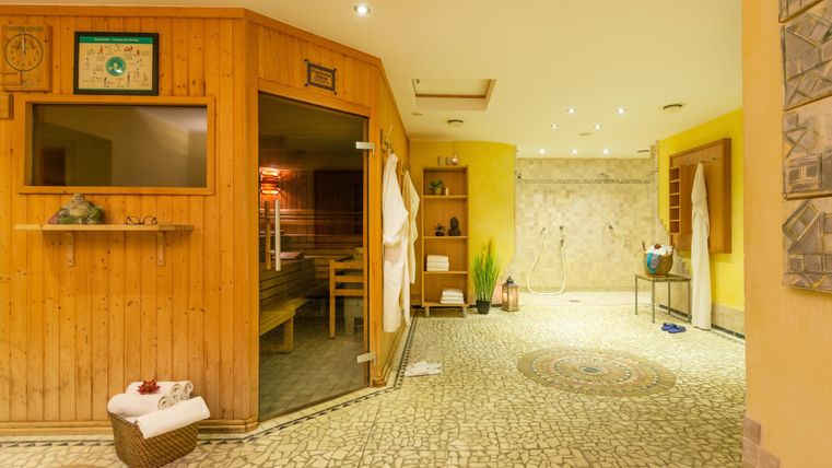 Ein entspannender Saunabereich mit Holzverkleidung und gemütlicher Atmosphäre. Der Raum ist hell erleuchtet und verfügt über einen schönen, gefliesten Boden.