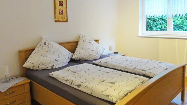 An inviting bedroom with a large double bed and bright bedcovers. The room has a window that lets in daylight.