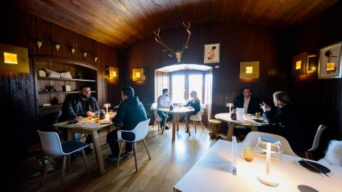 Een gezellige eetzaal met houten plafond en antieke decoraties. Gasten zitten aan tafels en genieten van hun maaltijd in een uitnodigende sfeer.