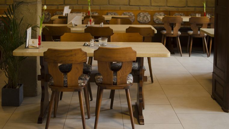 Ein gemütliches Restaurant mit Holztischen und -stühlen. Im Hintergrund sind weitere Sitzplätze und eine entspannte Atmosphäre zu sehen.
