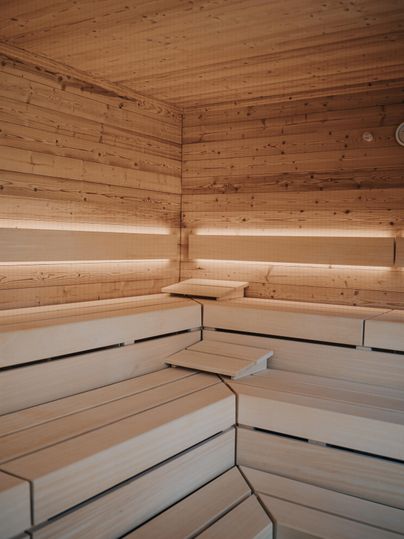 Een moderne sauna-ruimte met houten wandbekleding en zachte verlichting. De banken zijn ruim en uitnodigend.