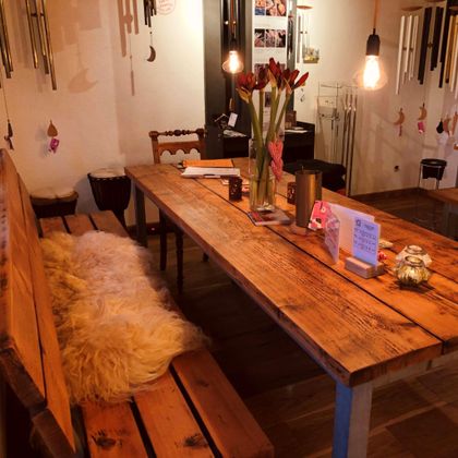 Een rustieke houten tafel met houten banken en een zacht tapijt. Op de tafel staan bloemen en kleine decoratieobjecten.