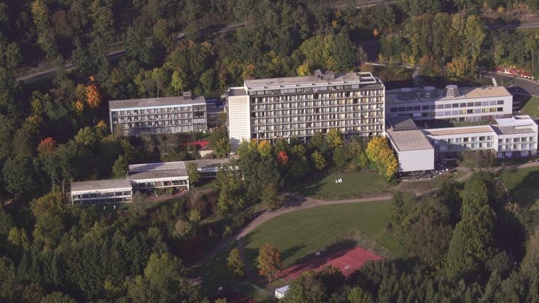 Eine große Anlage mit mehreren Gebäuden inmitten von Bäumen und Grünflächen. Der Standort bietet eine ruhige Umgebung, geeignet für Erholung oder Seminare.