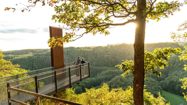 Aussichtspunkt Achterhöhe mit zwei Personen im Sonnenschein, umgeben von grüner Landschaft.