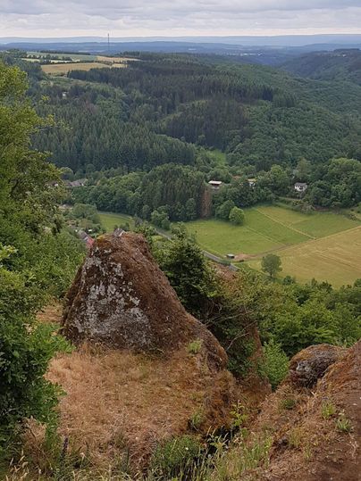 Een prachtig uitzicht op groene heuvels en bossen. Op de achtergrond zijn velden en een klein dorp zichtbaar.