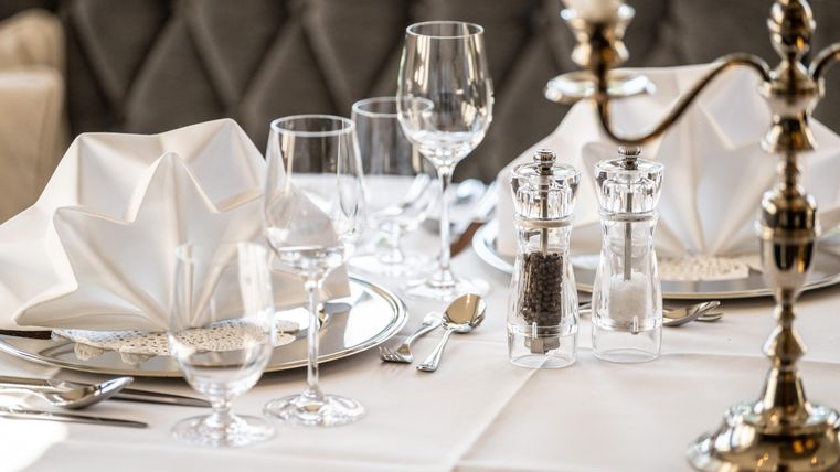 Ein elegant gedeckter Tisch mit weißen Servietten und Kristallgläsern. Die Atmosphäre ist feierlich und einladend.