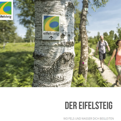 Een wandelpad door een groene landschap met een bord dat wijst op de Eifelsteig. Twee personen lopen ontspannen langs het pad.