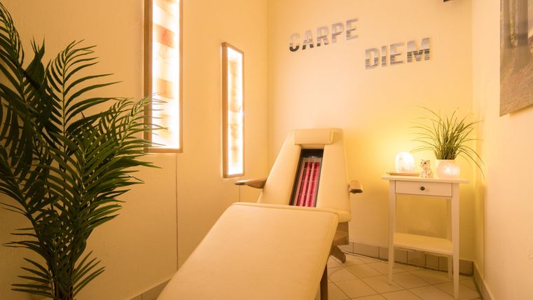 Ein entspannender Raum mit einem Liegestuhl und sanfter Beleuchtung. Pflanzen und dekorative Elemente schaffen eine beruhigende Atmosphäre.