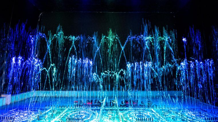 Water fountain organ with blue and green lights in a dark room.