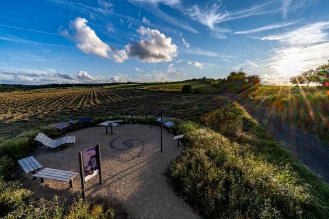 Eine gemütliche Sitzgelegenheit auf einem Feld bei Sonnenuntergang. Der Himmel ist mit Wolken und sanften Farben geschmückt.