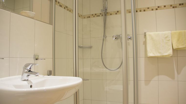 Een moderne badkamer met een douchecabine en een wastafel. Helder betegelde muren geven de ruimte een aangename sfeer.