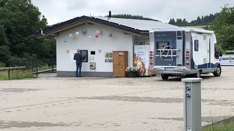A motorhome was parked in front of a small, modern building. A person is standing in front of an information desk.