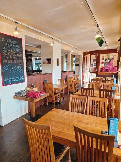 A cozy restaurant with wooden chairs and tables. A chalkboard with menu offerings hangs on the wall.