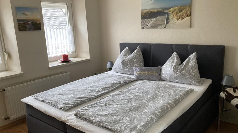 Een gezellig slaapkamer met een groot tweepersoonsbed en elegante kussens. Aan de muren hangen schilderijen, en de kamer heeft een uitnodigende sfeer.