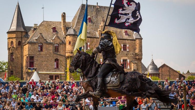 Ritter auf Pferd mit Fahne und im Hintergrund Burg Satzvey