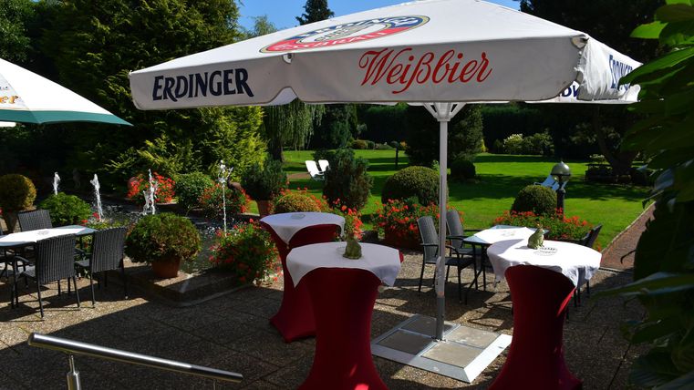 Ein einladender Garten mit Tischen und Sonnenschirmen. Die Atmosphäre ist entspannt und perfekt für gesellige Zusammenkünfte.