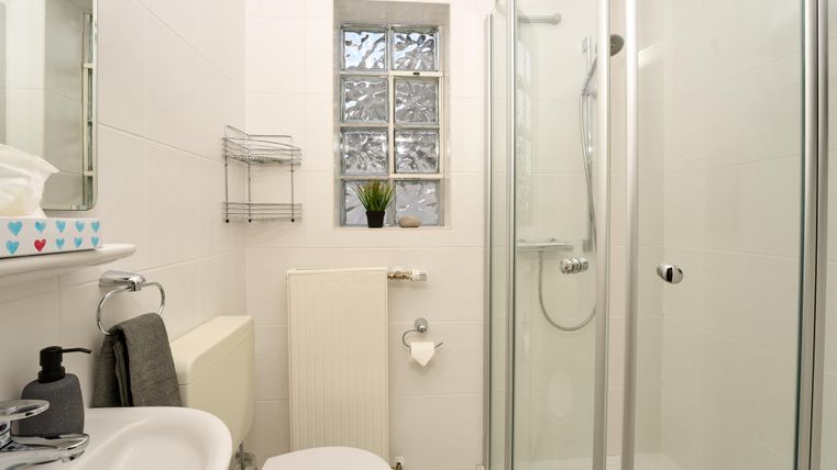 Ein modernes Badezimmer mit einer Dusche, einem WC und einem Waschbecken. Es ist hell und minimalistisch eingerichtet.