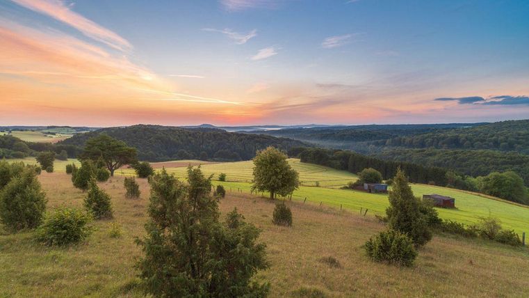 Een prachtige landschap met sanfte heuvels en weilanden. De lucht is gekleurd in warme kleuren van de schemering.