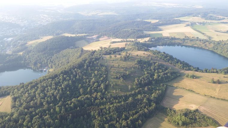 An airy landscape with gentle hills and forests. Two lakes are visible, surrounded by fields and meadows.