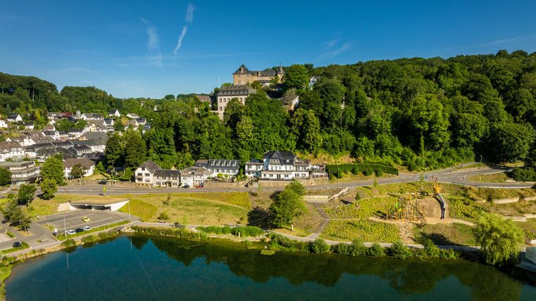 Eine Gruppe von Wanderern geht an einem großen Felsen vorbei. Im Hintergrund ist ein Hinweisschild zu sehen.