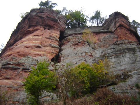 An impressive rock formation with steep cliffs and some trees. The sky is cloudy, giving the scene a mystical atmosphere.