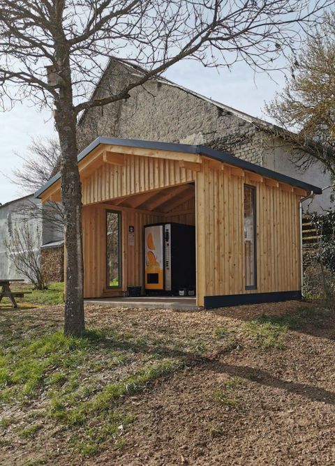Ein modernes Holzhaus mit großen Fenstern steht in einem grünen Garten. Es hat ein ansprechendes Dach und ist von Bäumen umgeben.