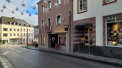 Een rustige straat met winkeltjes en een café. Boven de straat hangen decoratieve sterren.