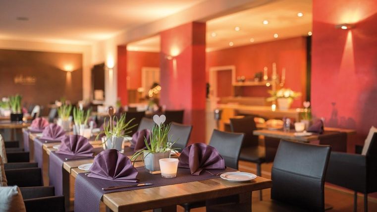 Ein elegantes Restaurant mit schön gedeckten Tischen. Die warme Beleuchtung und die moderne Einrichtung schaffen eine einladende Atmosphäre.