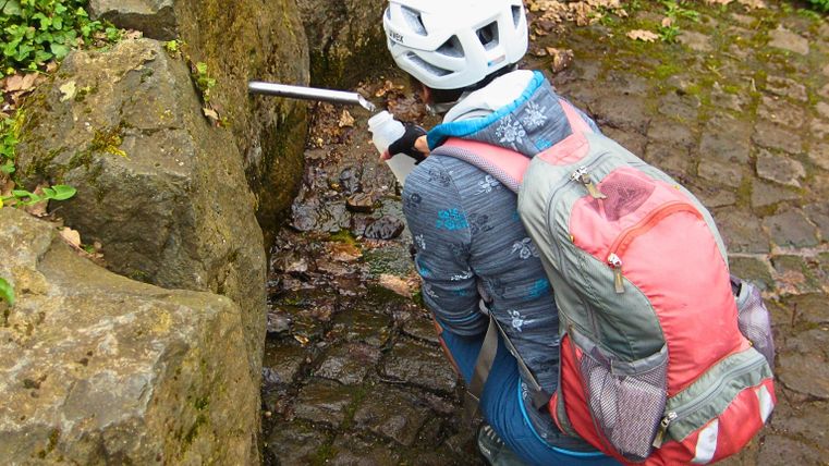 Fietster aan de bron, die haar drinkfles vult