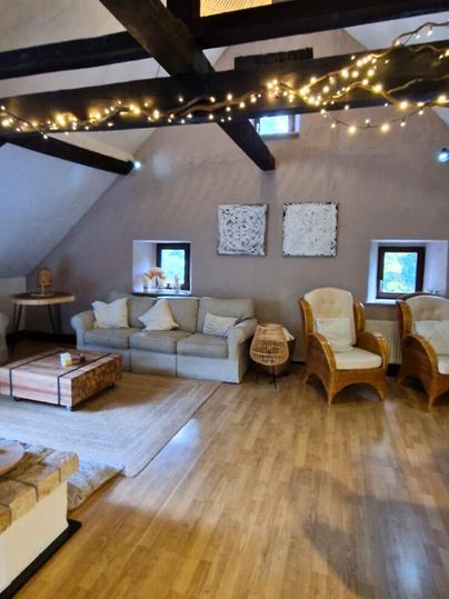 A cozy living space with wooden ceiling beams and stylish furnishings. The gentle lighting creates an inviting atmosphere.