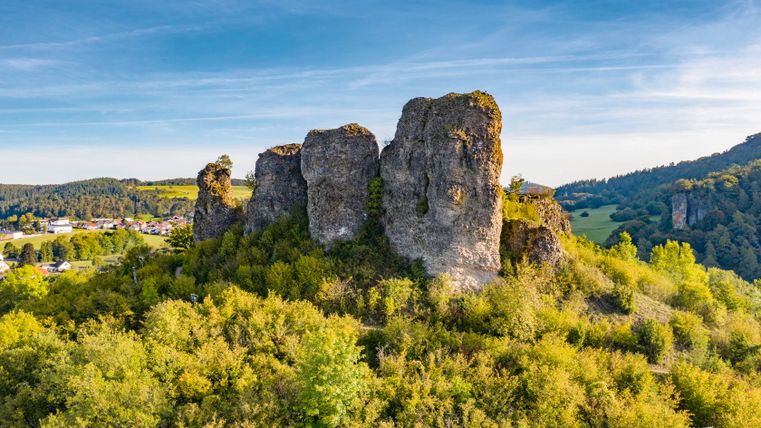 Felsformation der Gerolsteiner Dolomiten in der Eifel, umgeben von grüner Landschaft und blauem Himmel.